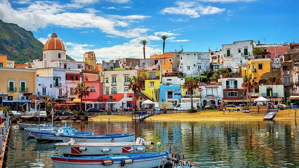 Le case colorate del porto di Ischia riflesse nell’acqua